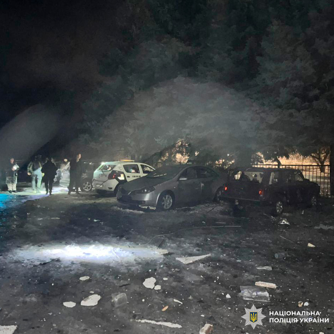 Нічна сцена з пошкодженими автомобілями та слідами руйнувань. На місці працюють правоохоронці.