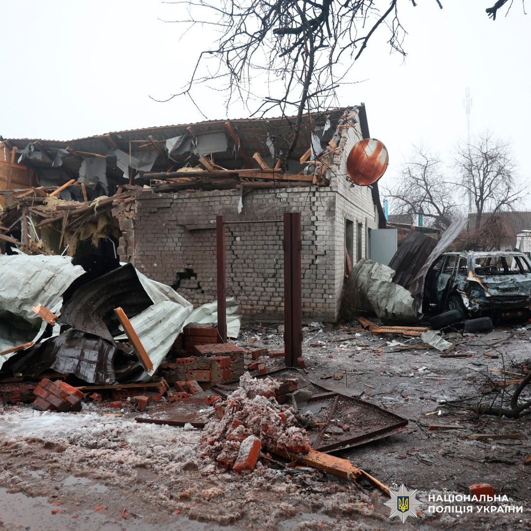 Зруйнована будівля з частково обваленим дахом та згорілим автомобілем.