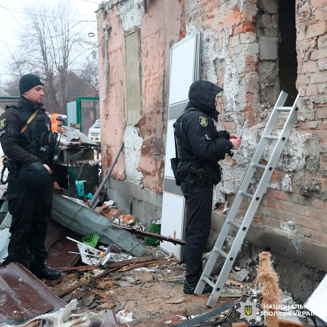 Поліцейські оглядають пошкоджену будівлю з великим отвором у стіні та уламками.