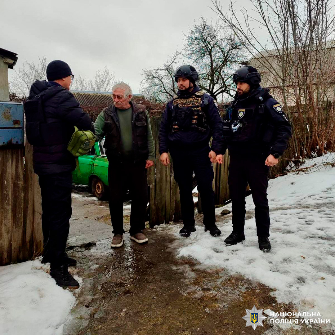 Поліцейські спілкуються з мешканцем громади, надаючи підтримку та інформацію в умовах холодної погоди.