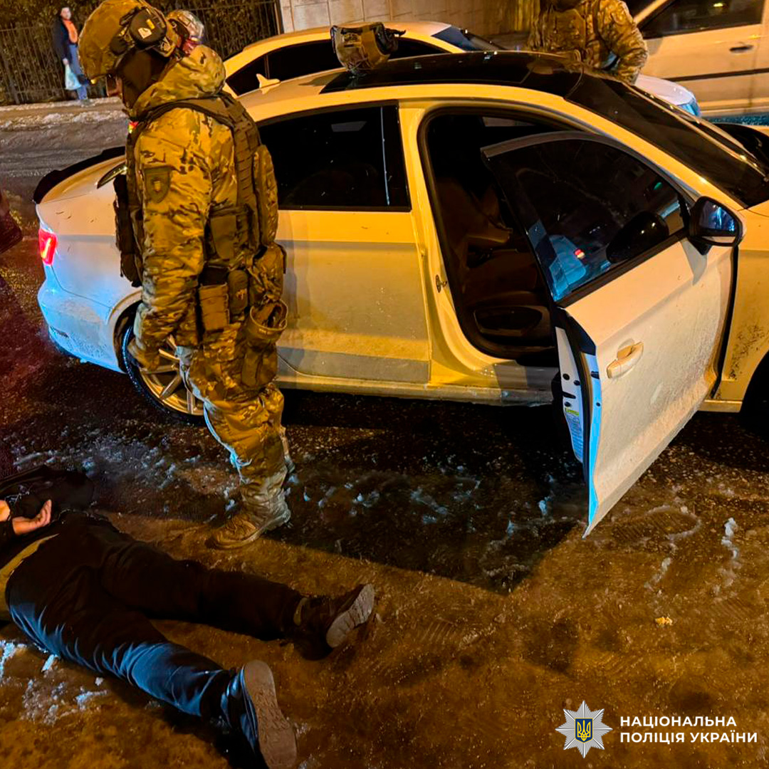 Поліцейські у бронежилетах проводять затримання підозрюваного просто на вулиці.