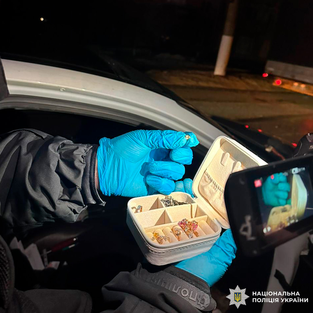 Поліцейський у рукавичках демонструє коробку з кільцями та прикрасами, зафіксовану на камеру як речовий доказ.
