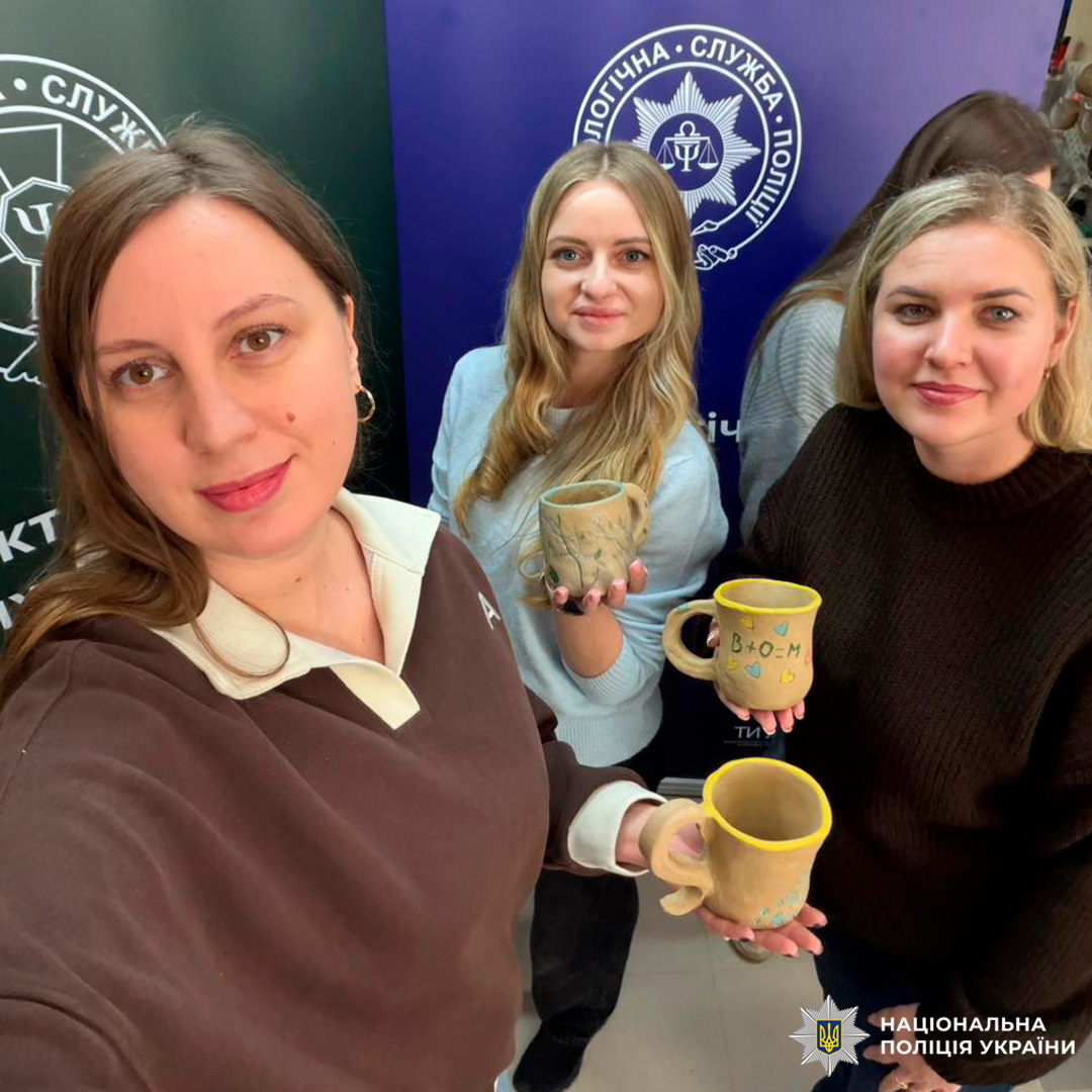 Троє учасників тримають керамічні горнятка, виготовлені під час майстерні.