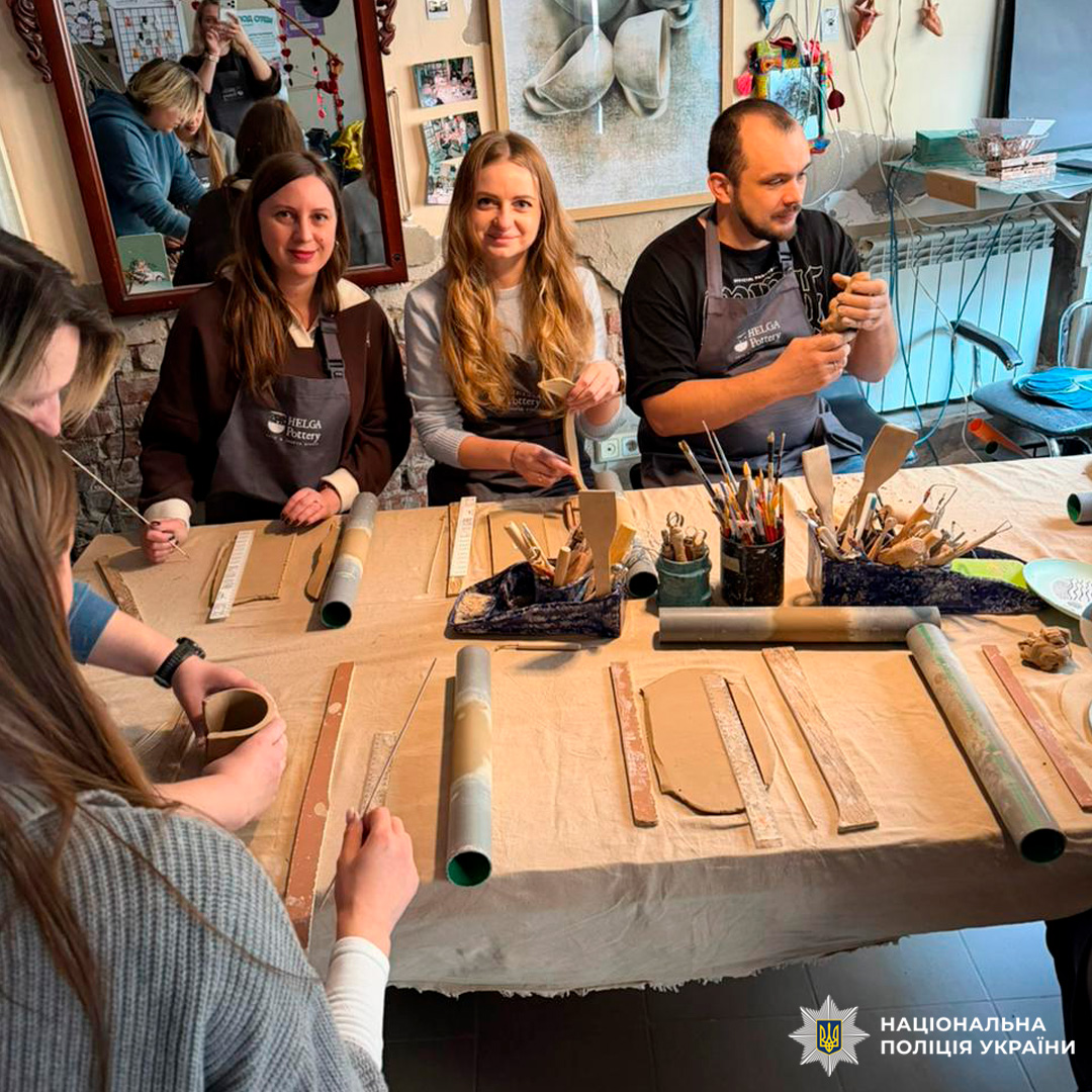 Група учасників майстерні працює за столом із глиною та інструментами.