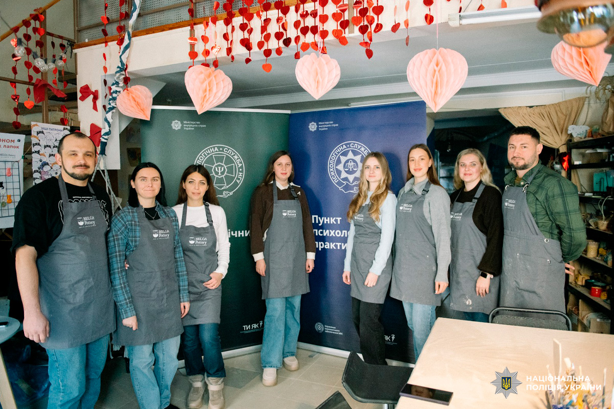 Група осіб у сірих фартухах на тлі банерів Психологічної служби.