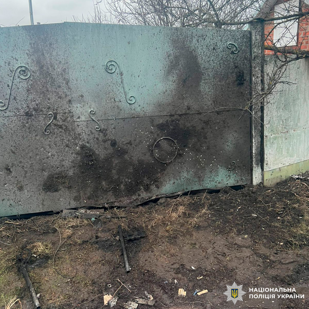 Пошкоджені металеві ворота зі слідами обгоряння та уламками на землі.