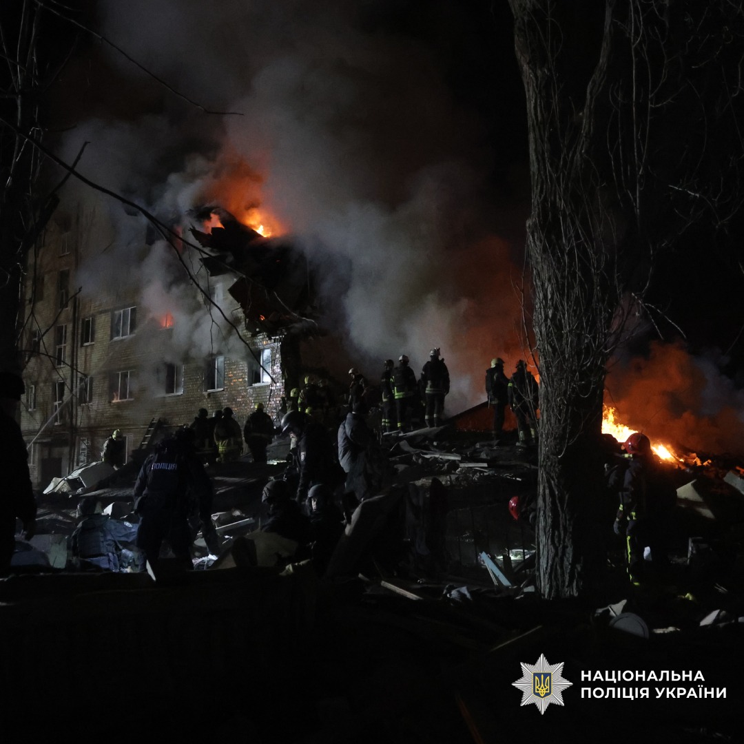 Пожежа у будівлі вночі: рятувальники та поліцейські працюють на місці події.