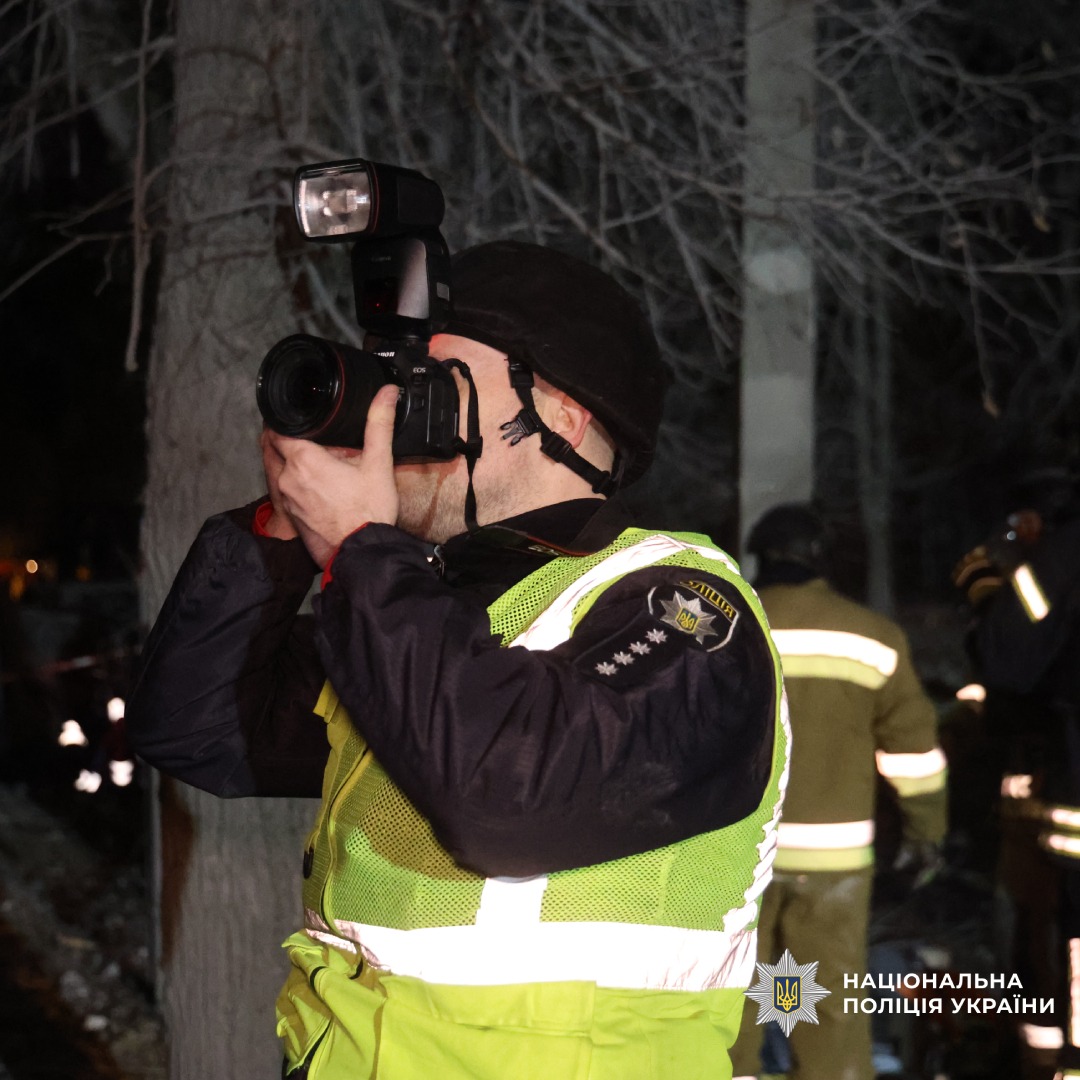 Працівник Національної поліції України здійснює фотозйомку під час нічної операції.