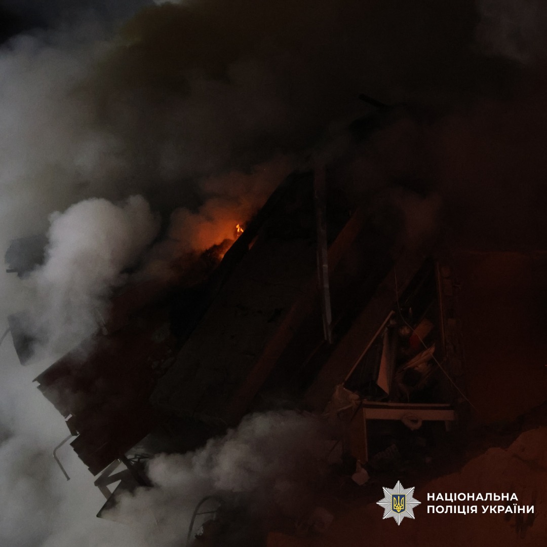 Зруйнована будівля з осередком займання та густим димом.