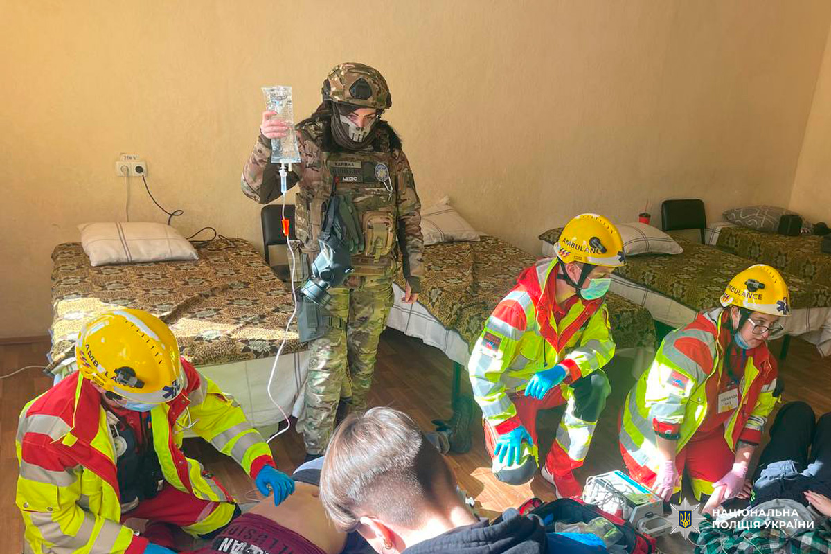 Медики у захисній формі надають допомогу постраждалому всередині приміщення.