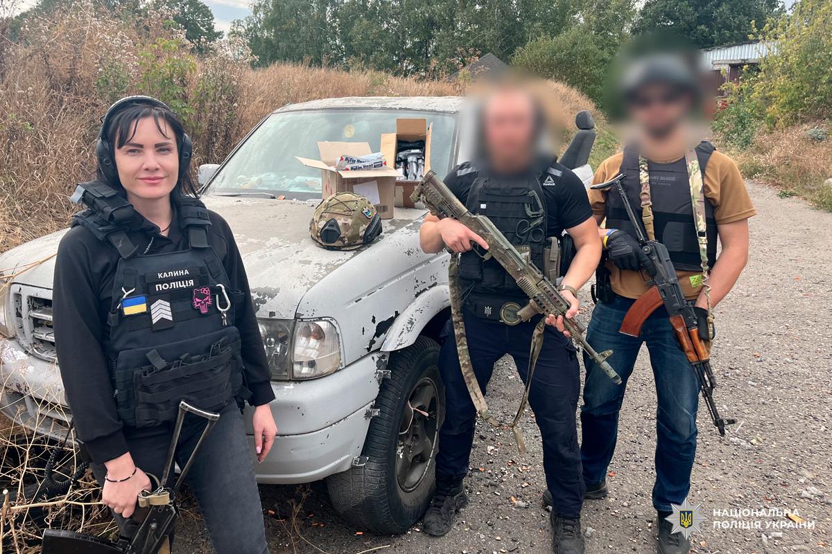 Співробітники у тактичному спорядженні біля білого автомобіля, на капоті - коробки з речами та шолом.