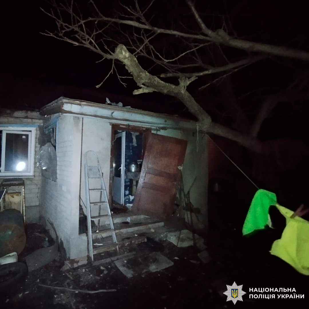 Нічна сцена: невелика будівля з видимими руйнуваннями та розкиданими уламками біля входу.