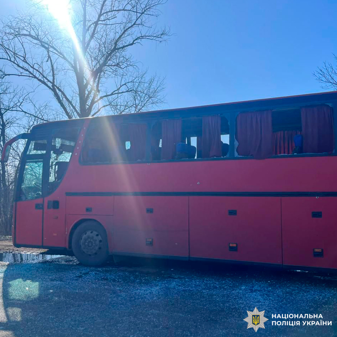 Червоний автобус із червоними шторами та синіми сидіннями, припаркований уздовж дороги в сільській місцевості.