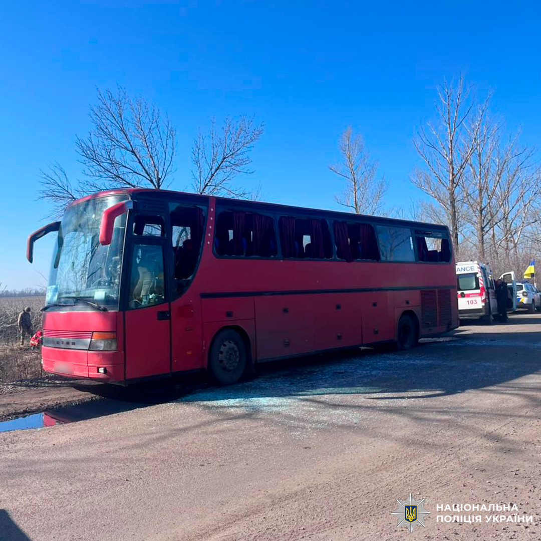 Червоний автобус із червоними шторами та синіми сидіннями, припаркований уздовж дороги в сільській місцевості.