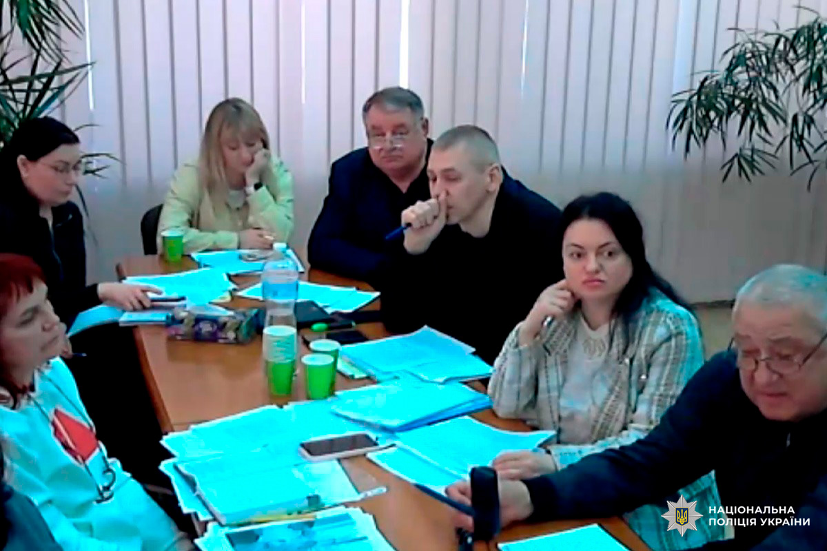 Учасники наради Національної поліції України сидять за столом із документами та ноутбуками.