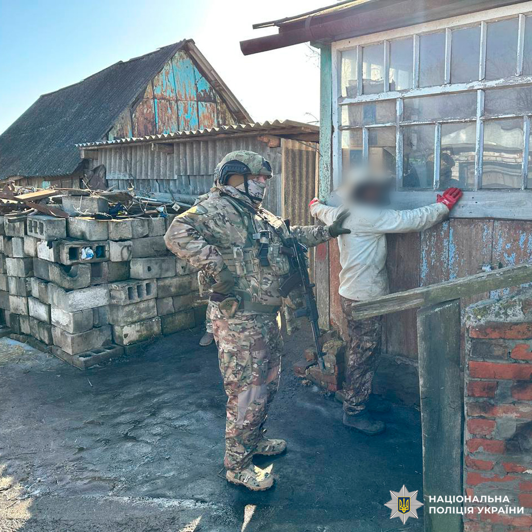 Затримання та перевірка громадянина правоохоронцем у камуфляжі з автоматичною зброєю.