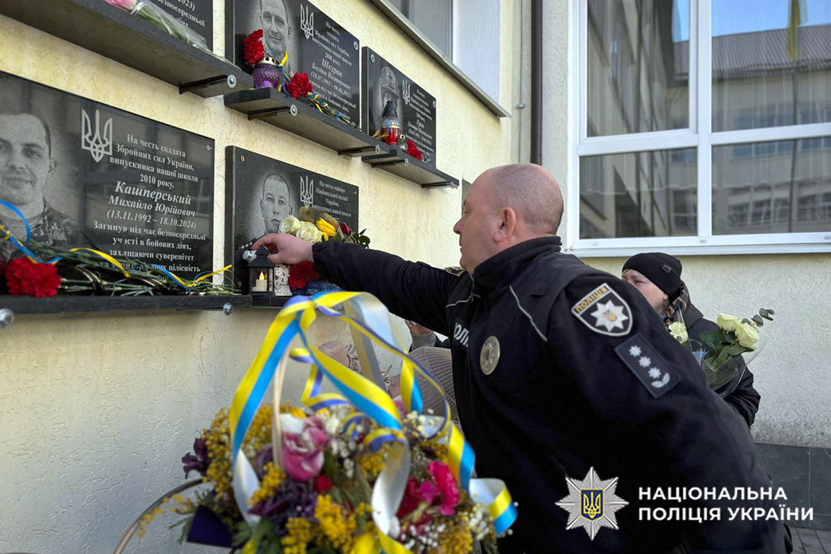 Поліцейський кладе квіти до меморіальної дошки