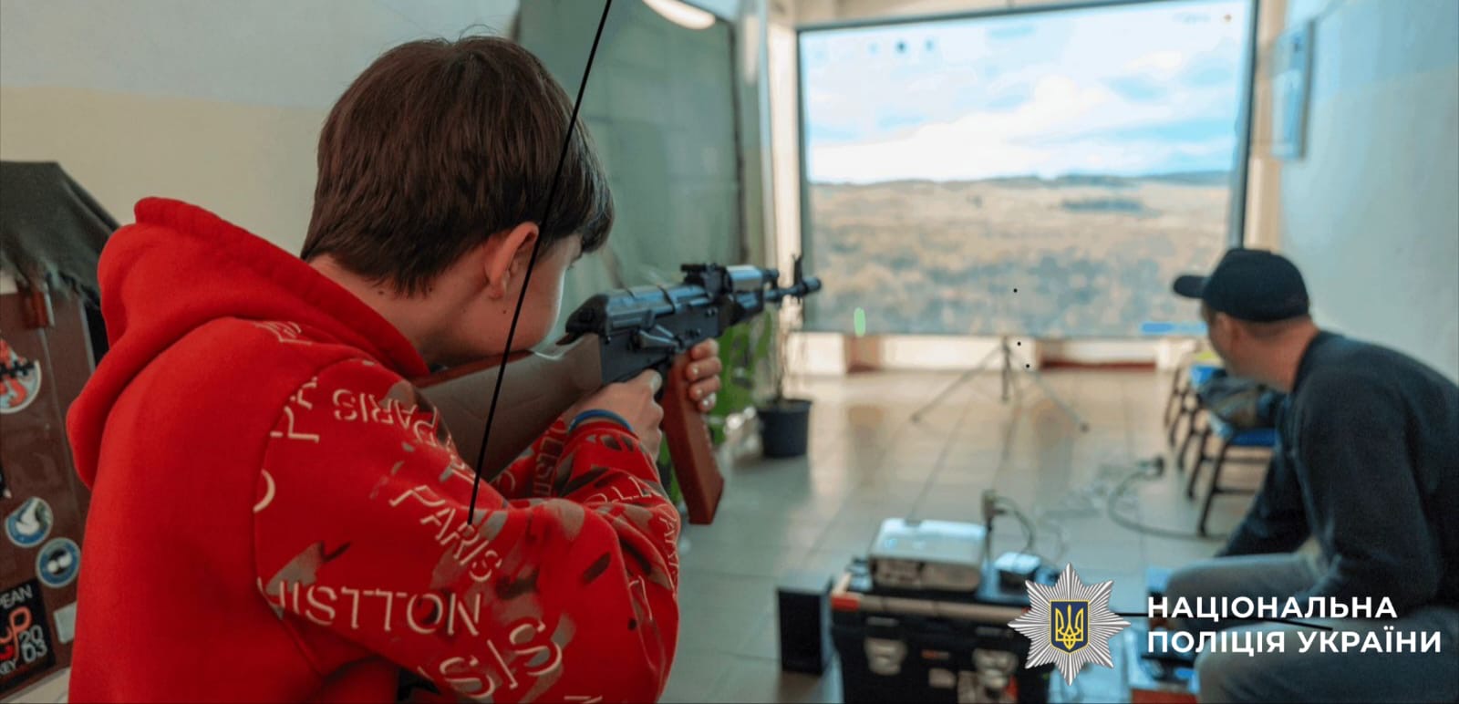 На фото зображений учень, який стріляє з імітованого автомату