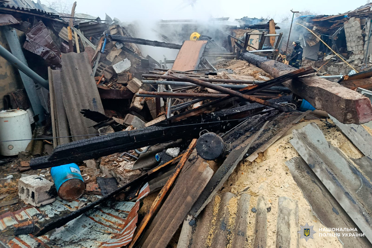 Вщент зруйновані будівлі, завали з деревини та шиферу, здіймається дим.