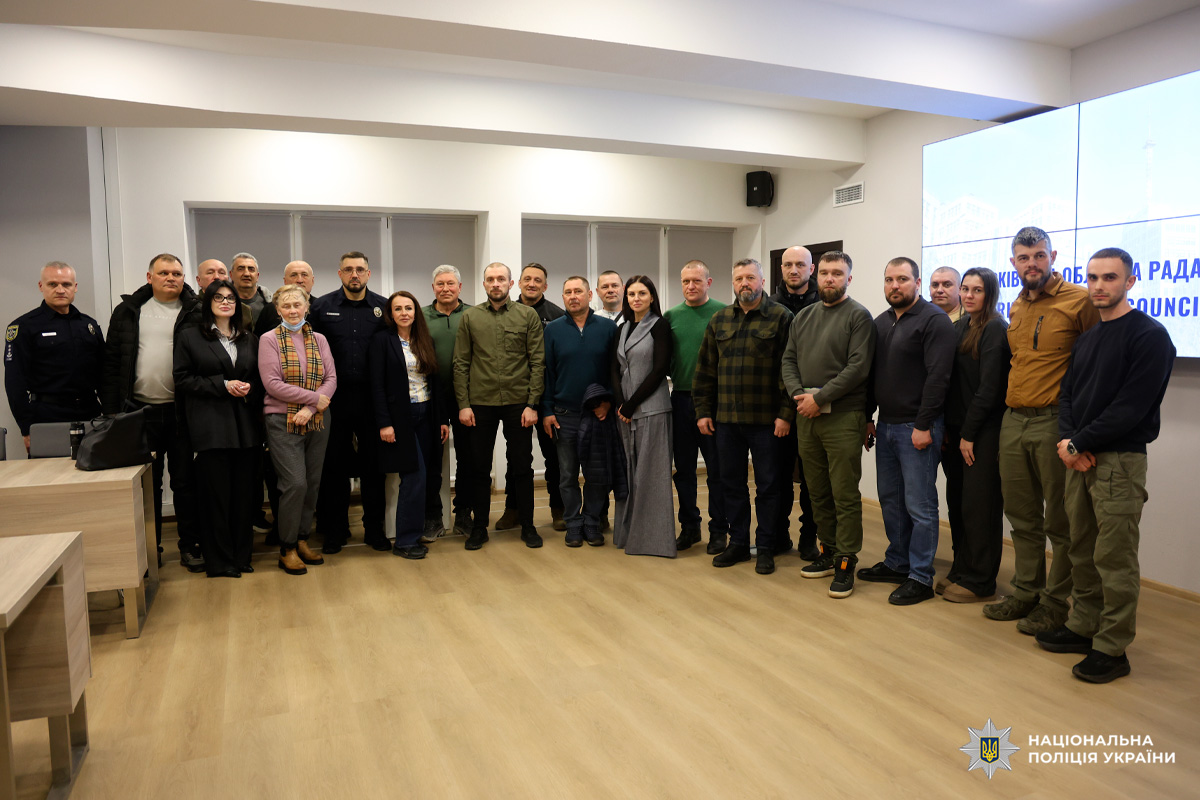 Колективне фото великої групи людей (чоловіків та жінок) у приміщенні. Частина присутніх у формі поліції, частина - у цивільному одязі.