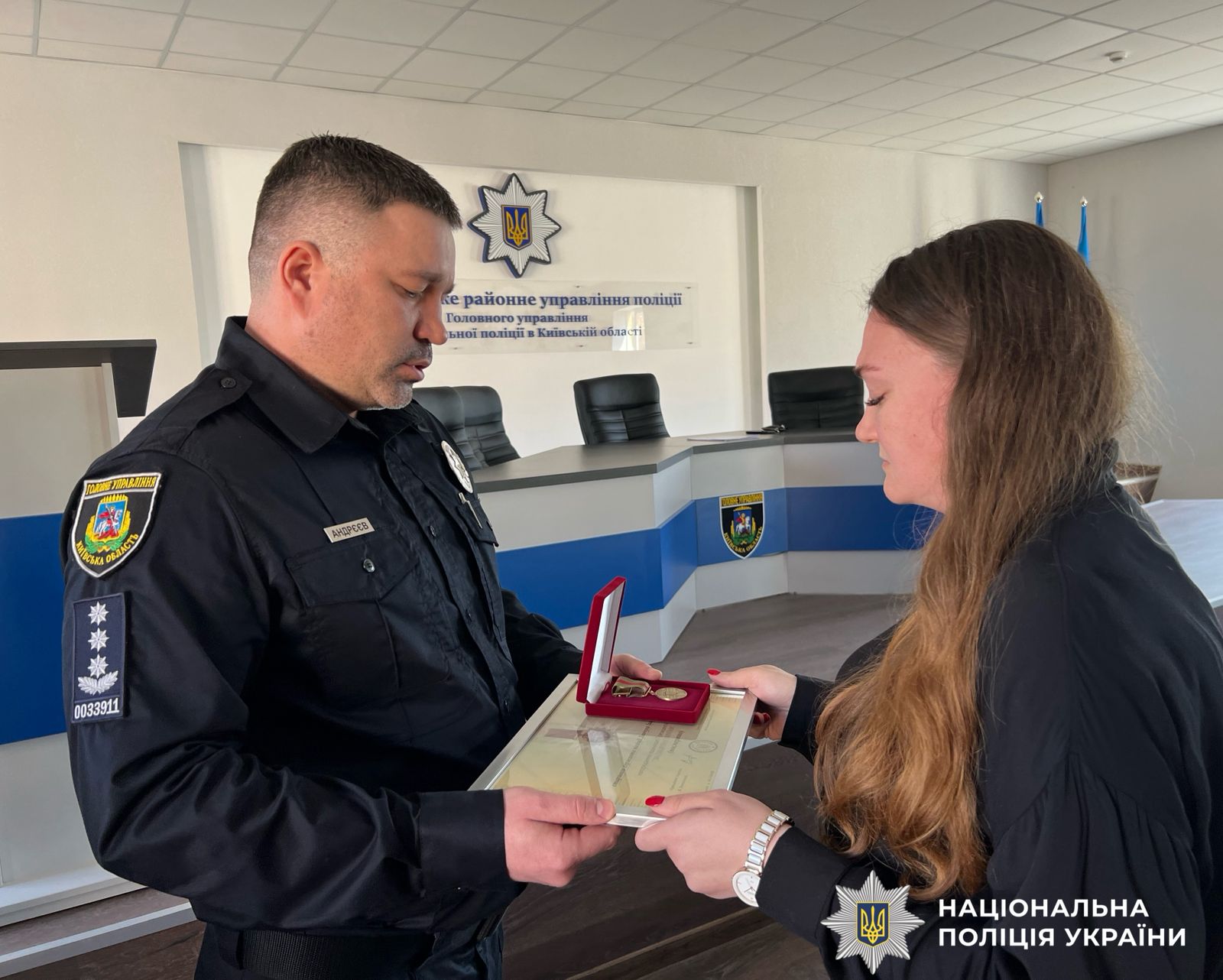 Поліцейський вручає нагороду жінці.