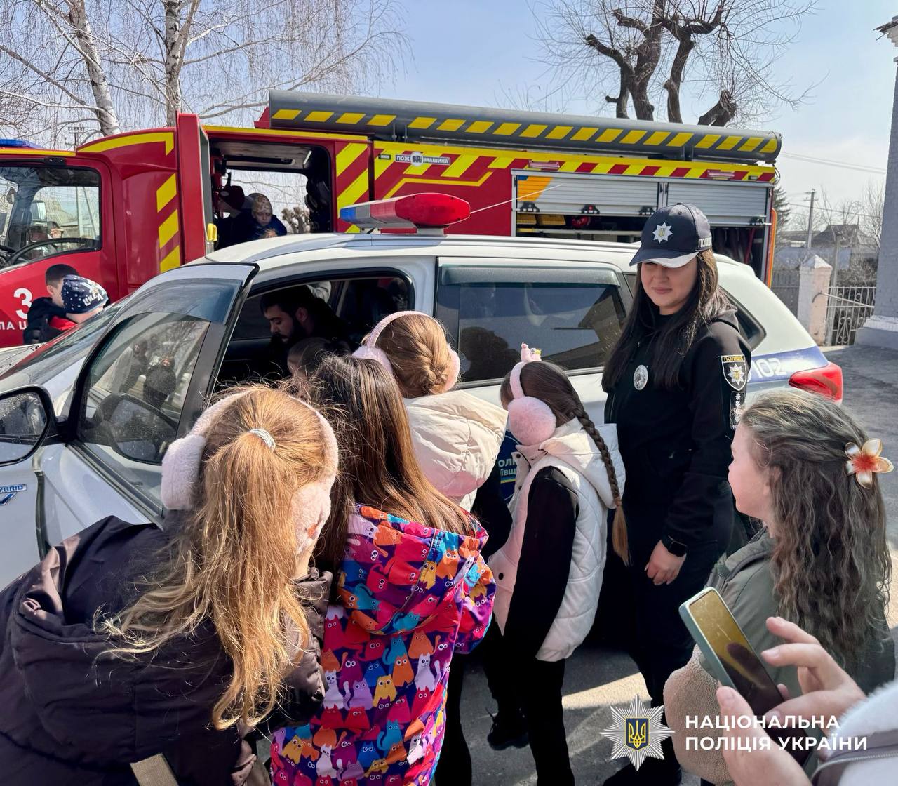 На фото зображено поліцейська, яка розповідає про безпеку дітям