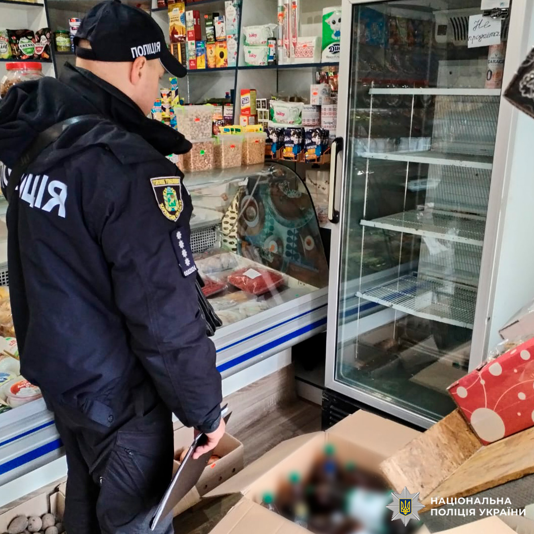 Cпівробітник поліції з блокнотом серед полиць із продуктами.