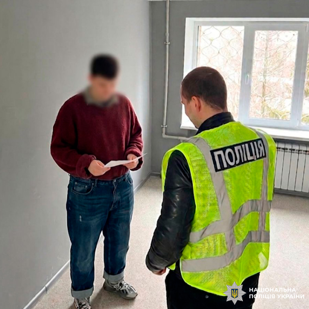 Представник поліції спілкується з особою, яка тримає документ.