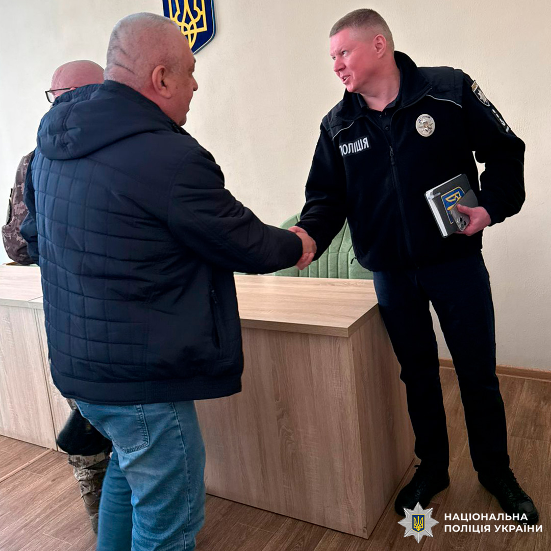 Поліцейський у формі тисне руку громадянину під час офіційної зустрічі в кабінеті.