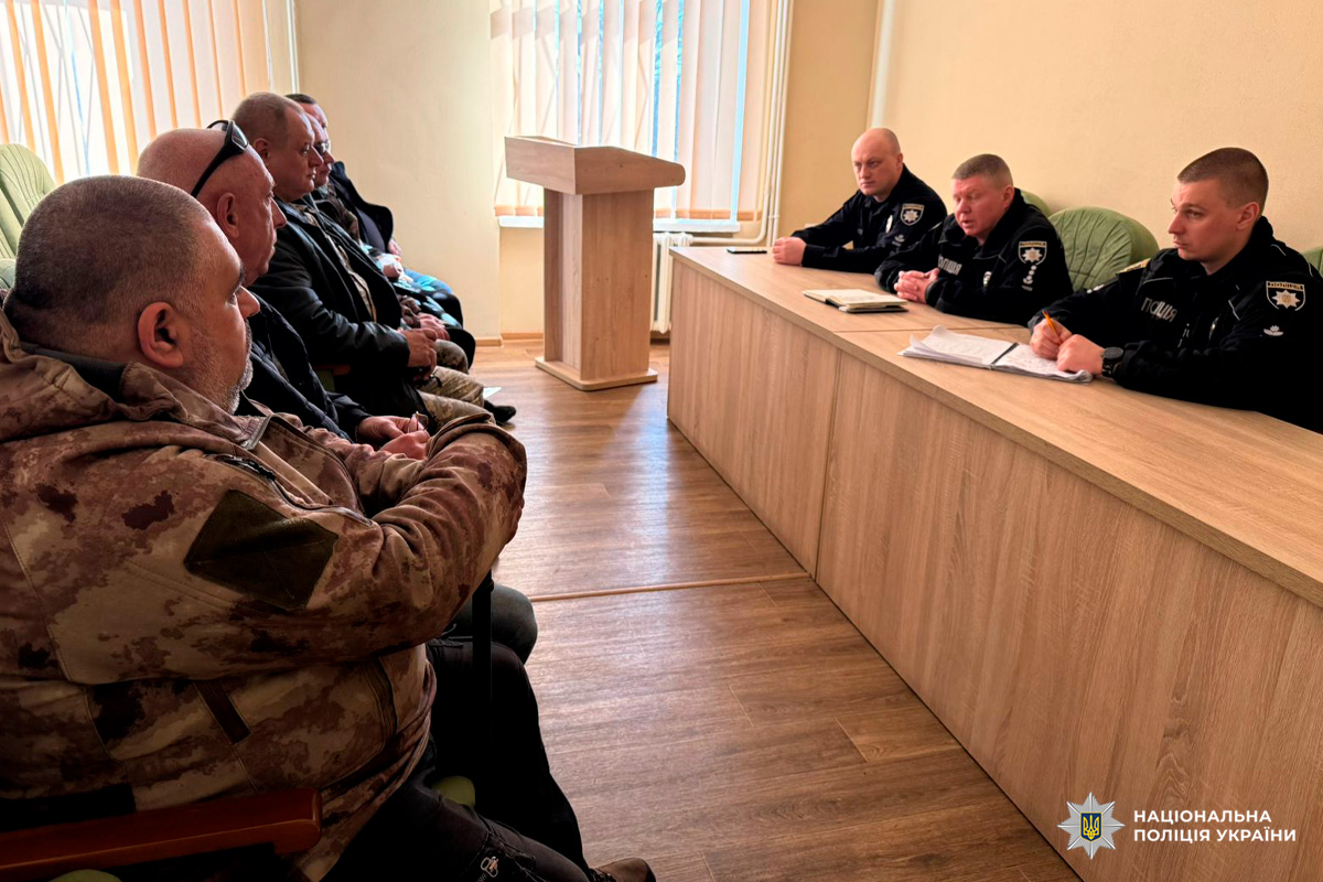 Поліцейські у формі за довгим столом ведуть обговорення з цивільними учасниками.