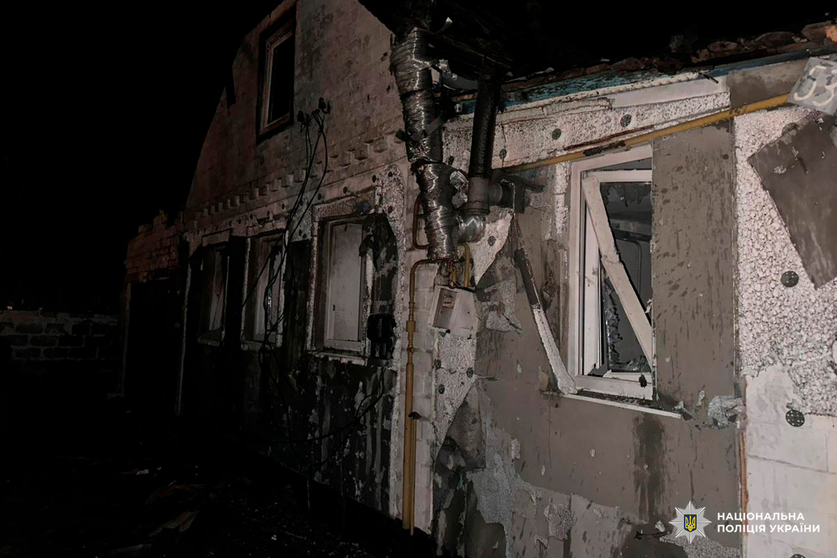 Пошкоджена будівля вночі: обгорілі стіни, вибиті вікна, оголені труби та кабелі.