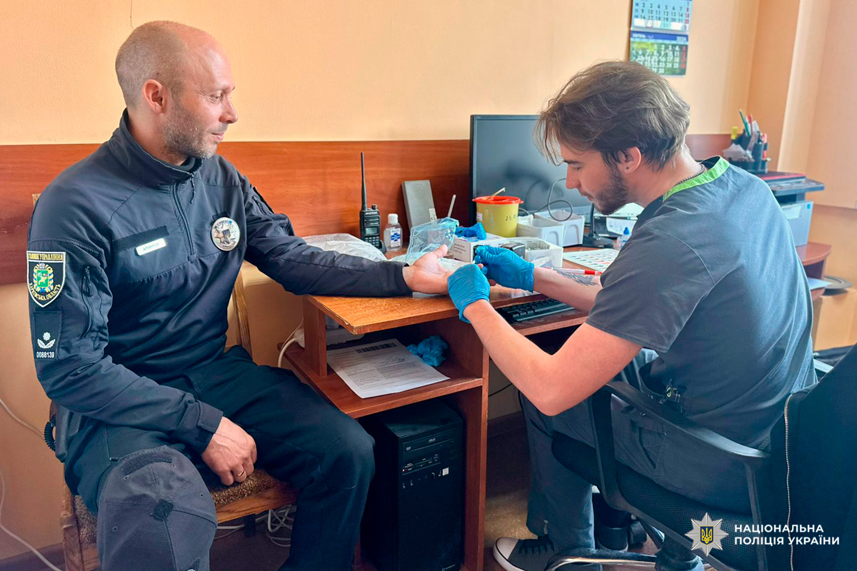 Медик у рукавичках бере зразок крові у поліцейського.