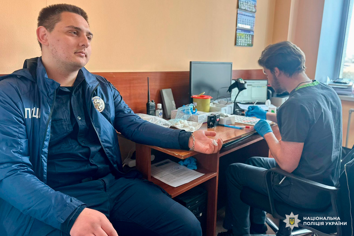 Поліцейський після забору крові, медик працює з матеріалами.