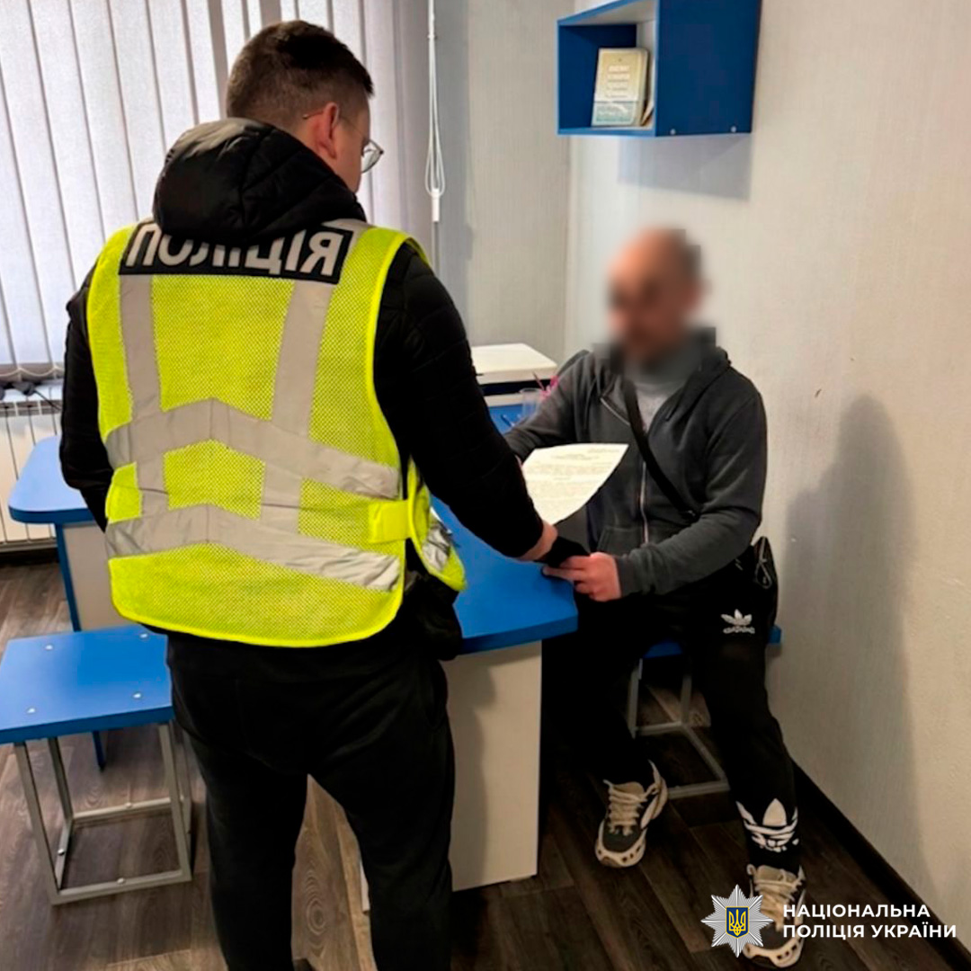 Працівник Нацполіції здійснює офіційне оформлення документів у присутності громадянина.