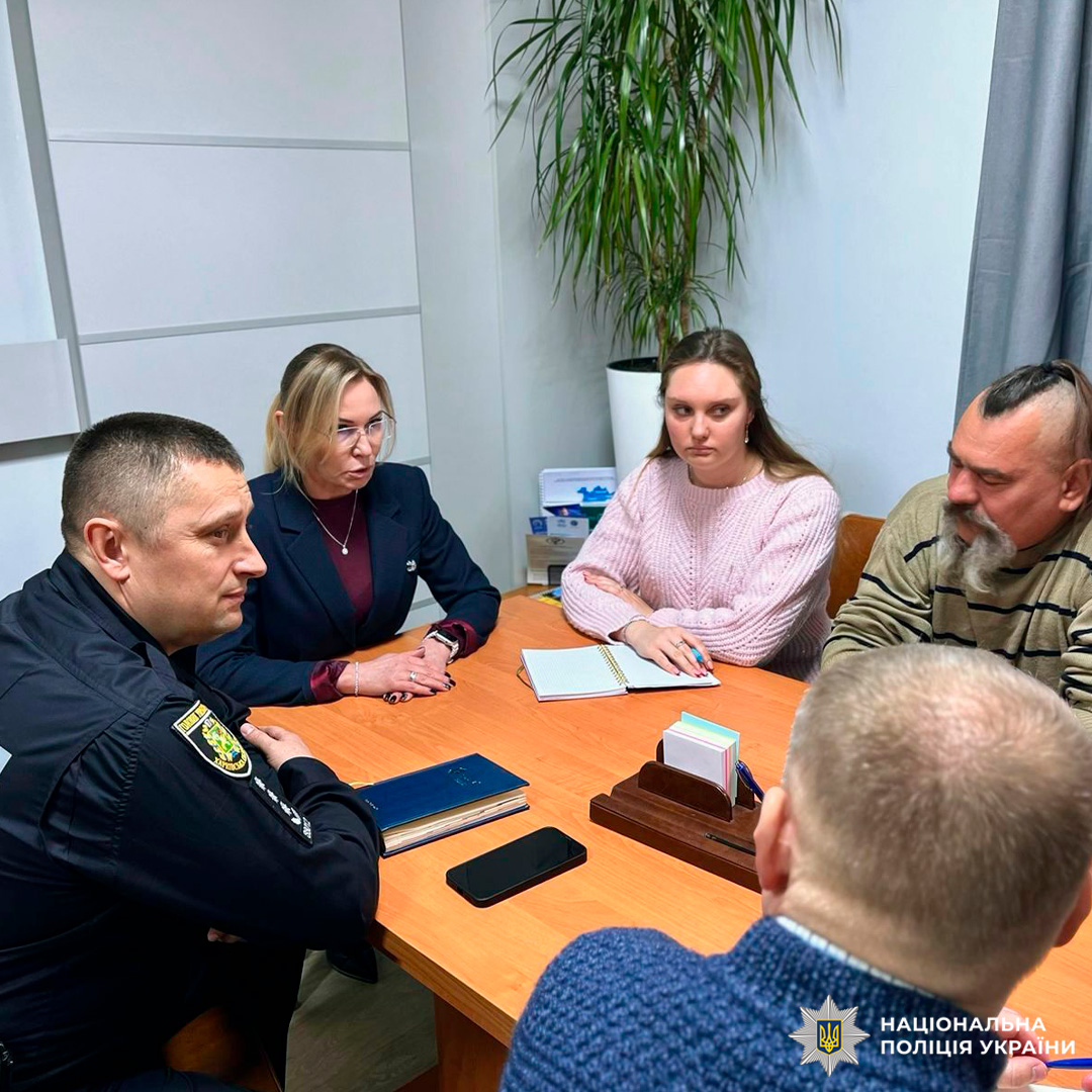 Шестеро учасників засідання сидять за дерев’яним столом у службовому кабінеті. Серед них  представник Національної поліції України у формі, інші в цивільному одязі. На столі - блокноти, телефон, органайзер.