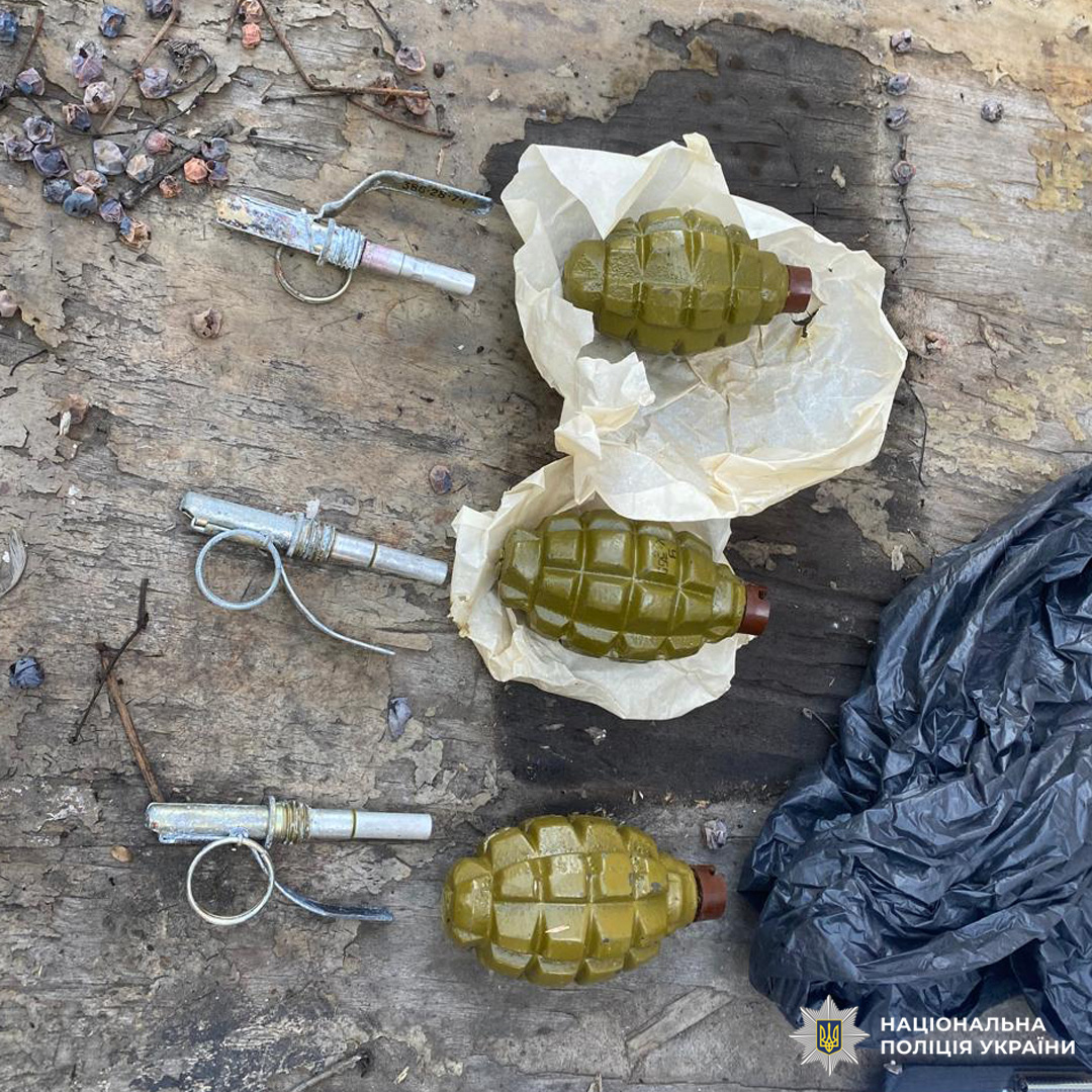 На дерев’яній поверхні лежать три гранати з запалами та пакуванням, поруч чорний пакет.