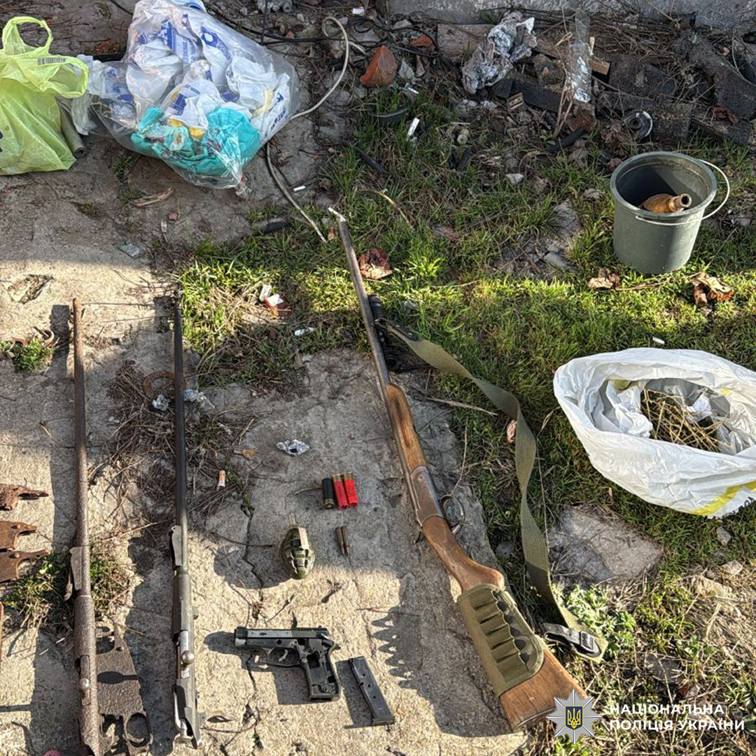 На траві та бетоні лежать гвинтівки, пістолет, патрони й граната, поруч пакети та контейнер.