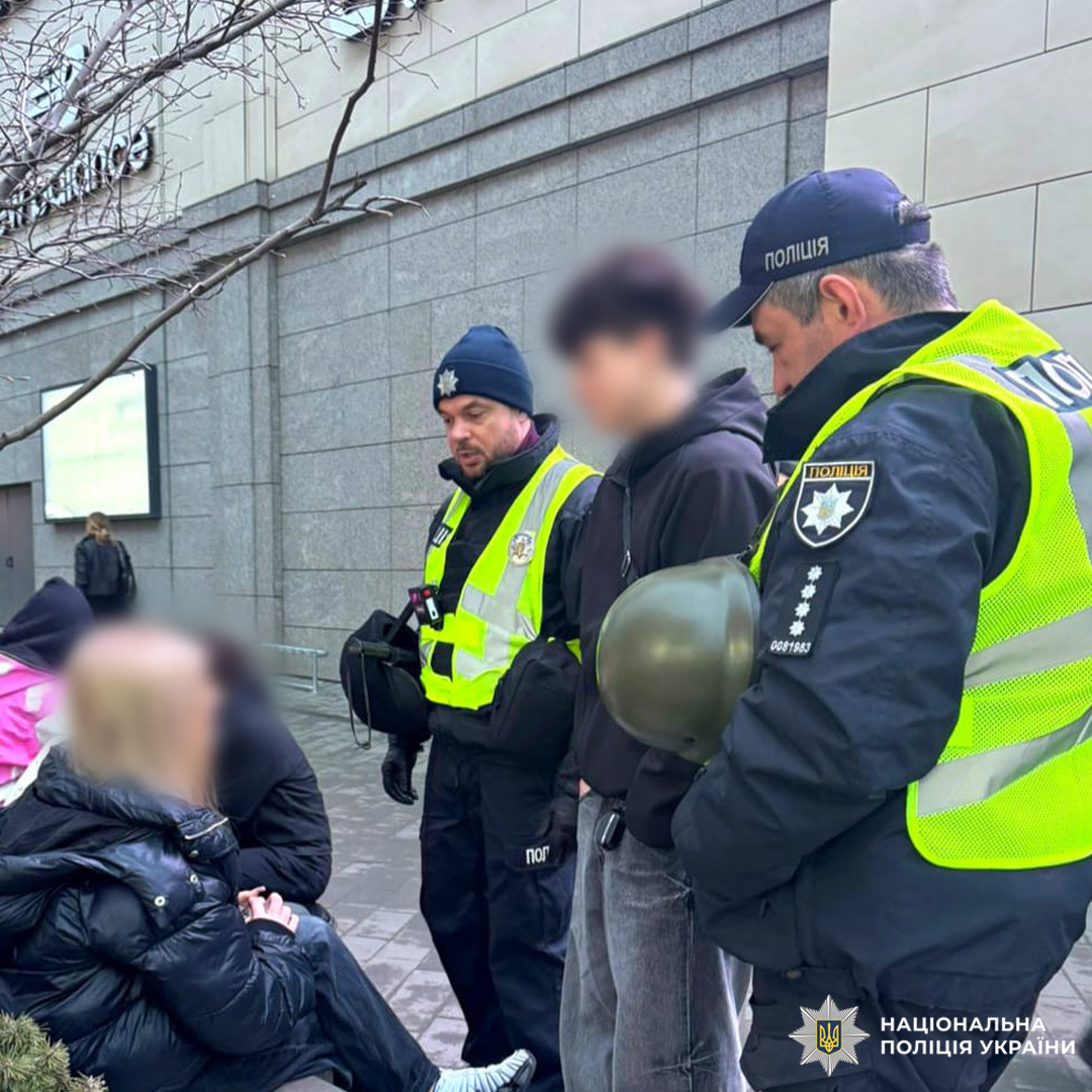 Поліцейські у формі та світловідбивних жилетах здійснюють перевірку громадян на міській вулиці.