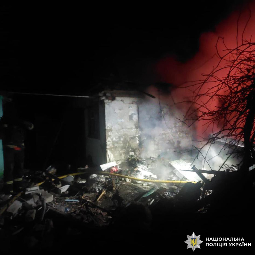 Зруйнована будівля вночі, уламки та дим.