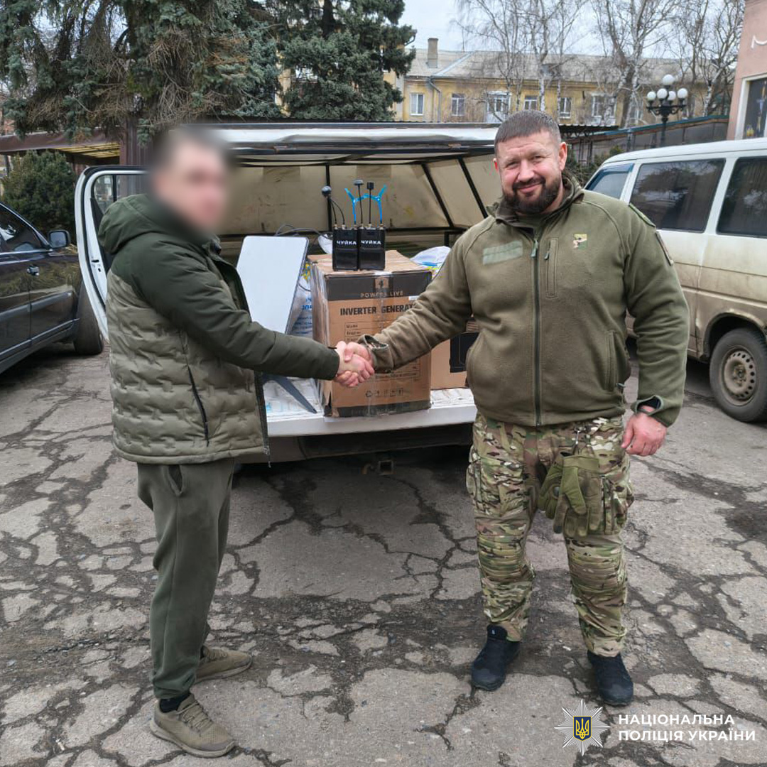 Двоє чоловіків тиснуть руки біля автомобіля з коробками обладнання.