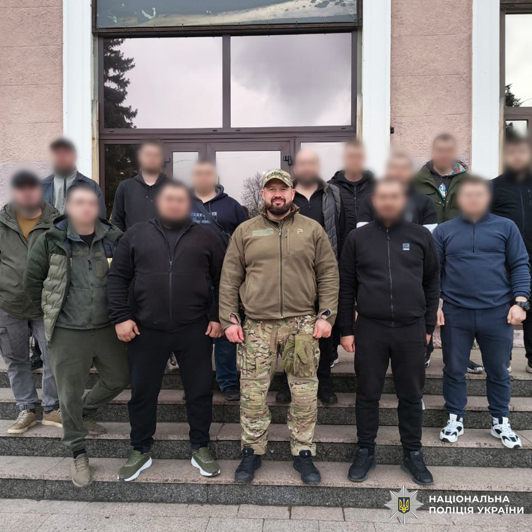 Група з п’ятнадцяти осіб на сходах перед будівлею.