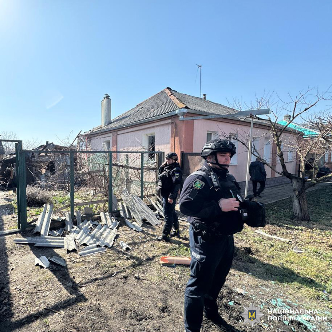 Поліцейські у захисному спорядженні проводять огляд пошкодженого житлового будинку після вибуху.