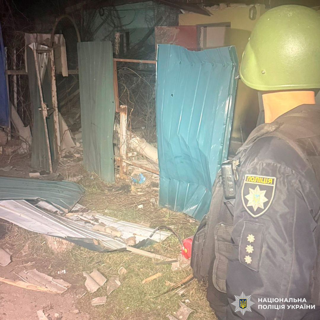 Поліцейський біля зруйнованої металевої конструкції вночі.