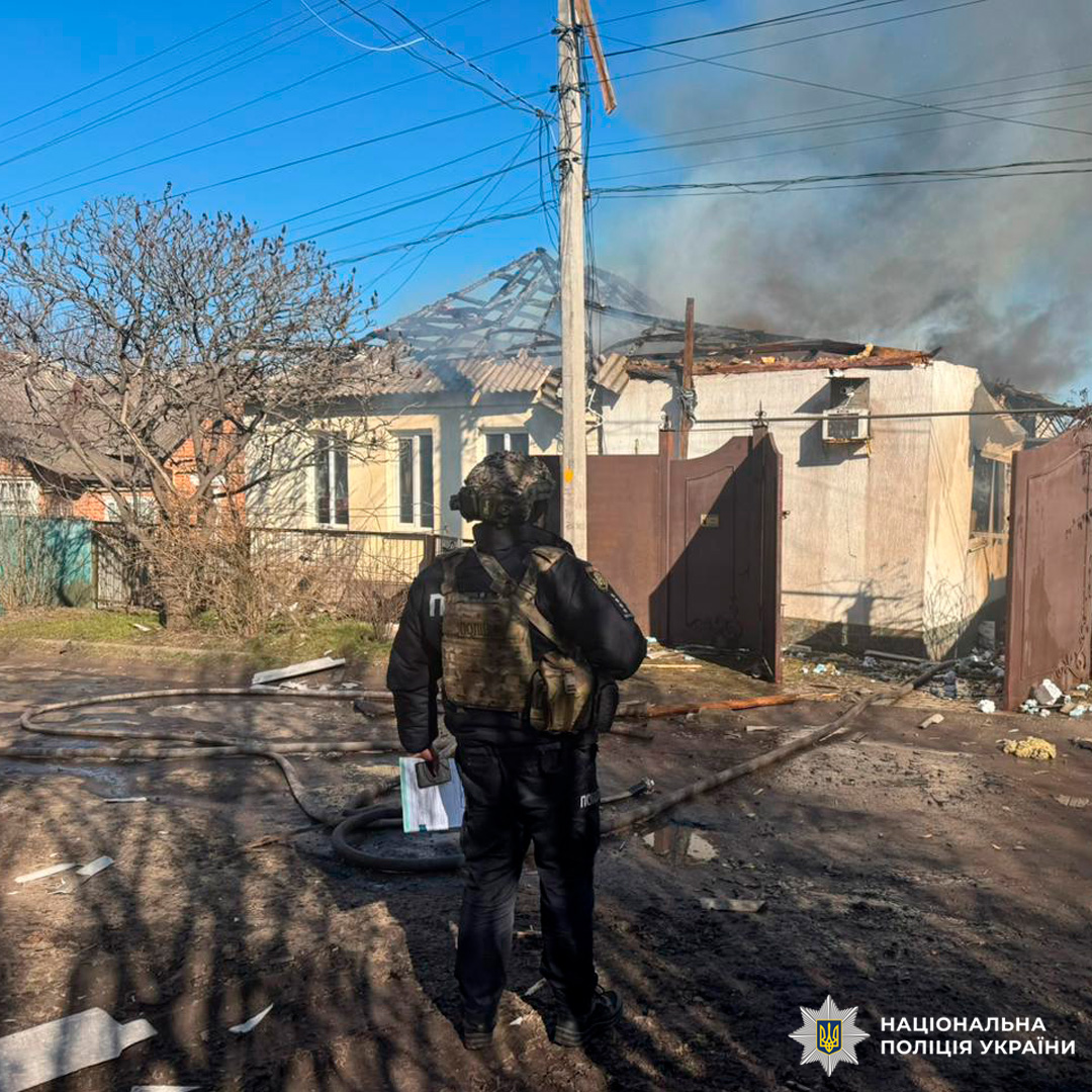 Поліцейський біля будинку зі зруйнованим дахом.