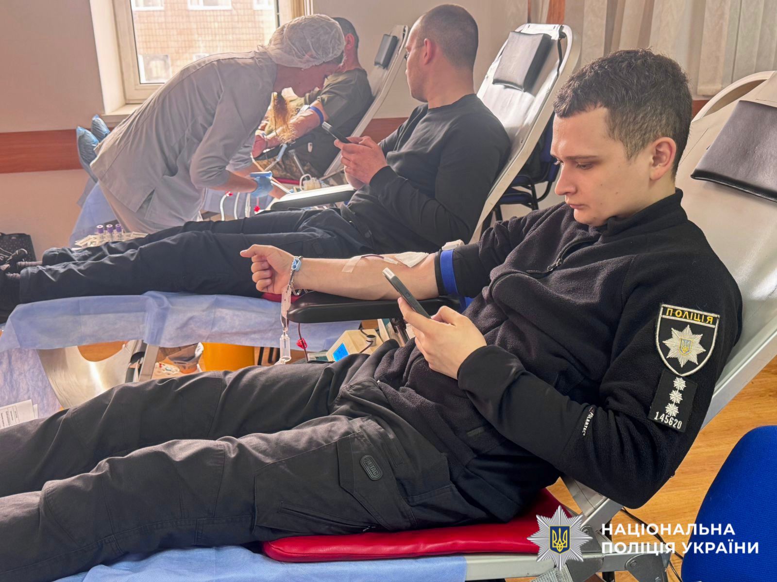 На фото зображено як поліцейський здає кров.