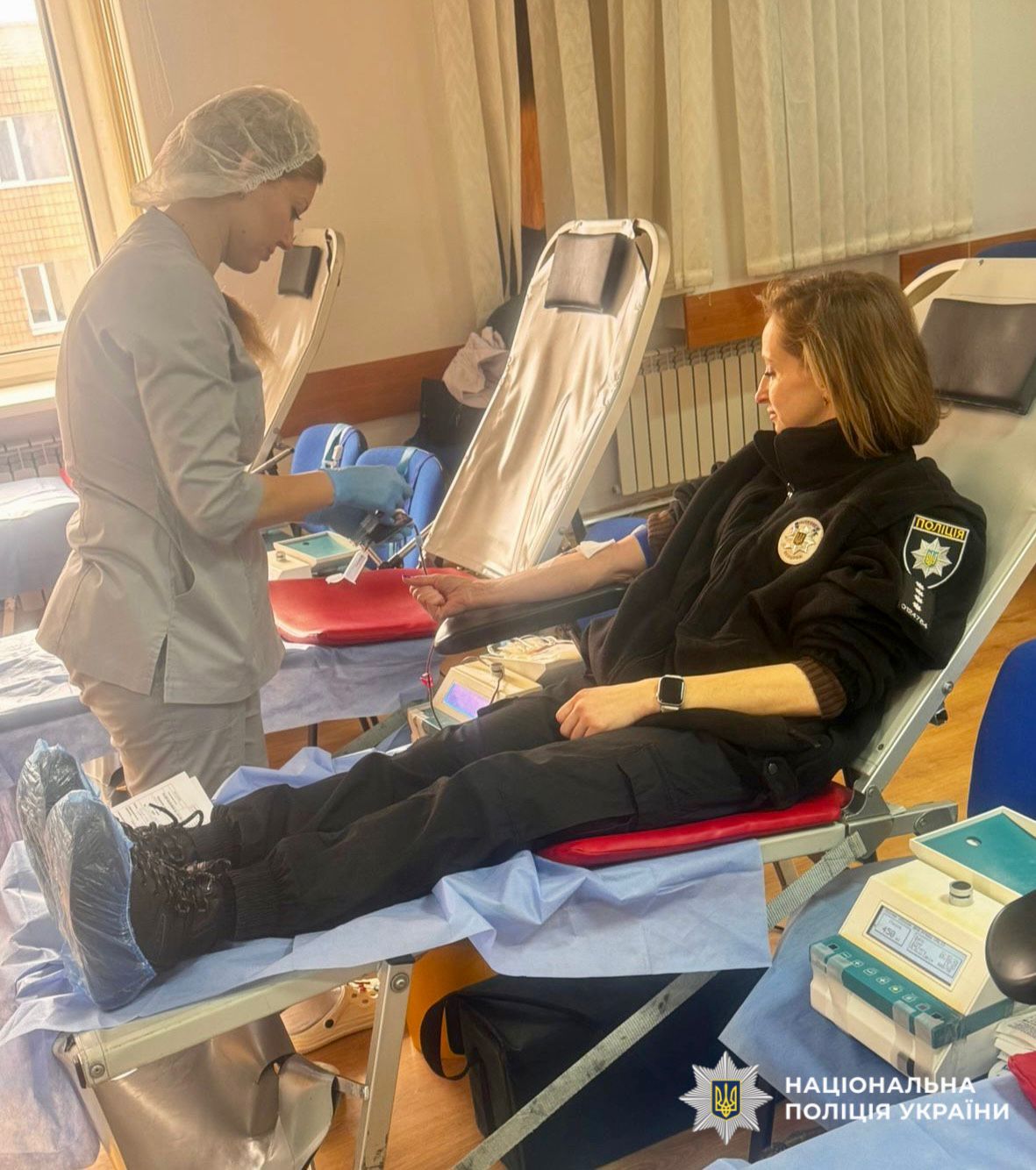 На фото зображено як поліцейський здає кров.