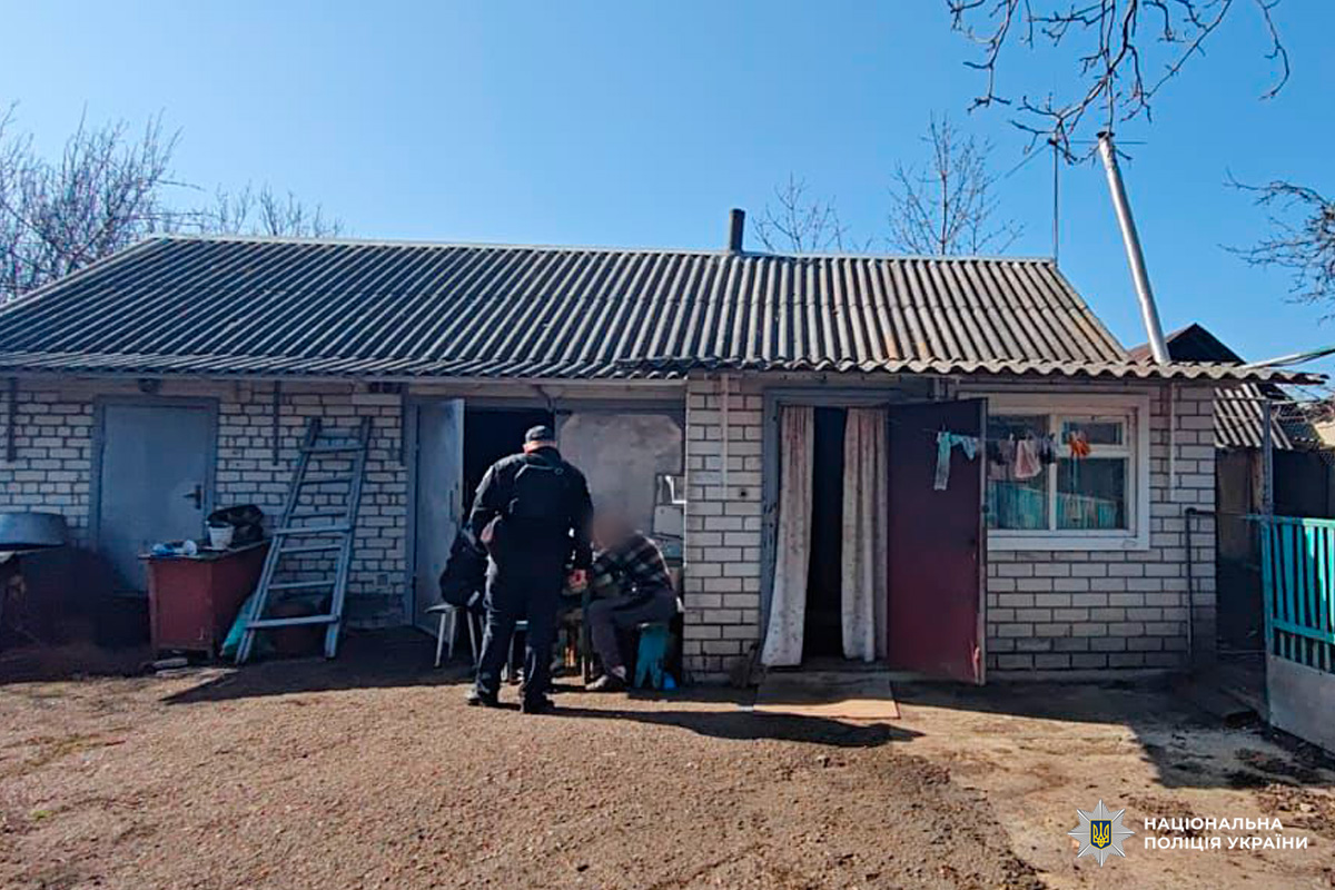 Поліцейський спілкується з мешканцем біля будинку.