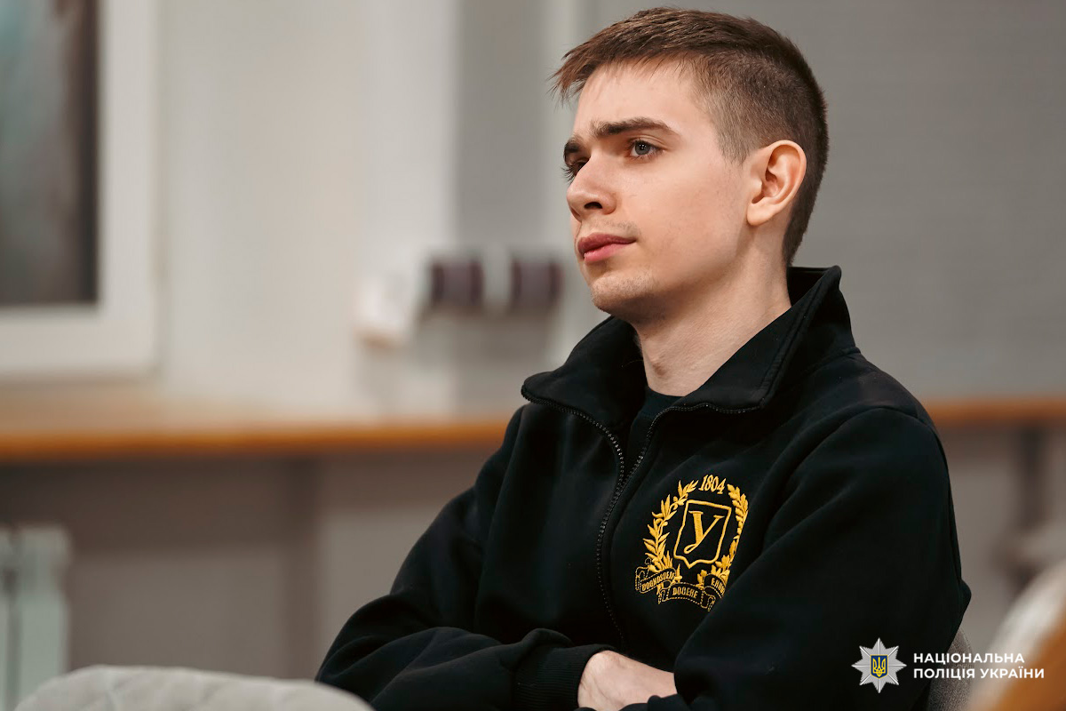 Учасник заходу в темній куртці з емблемою на грудях