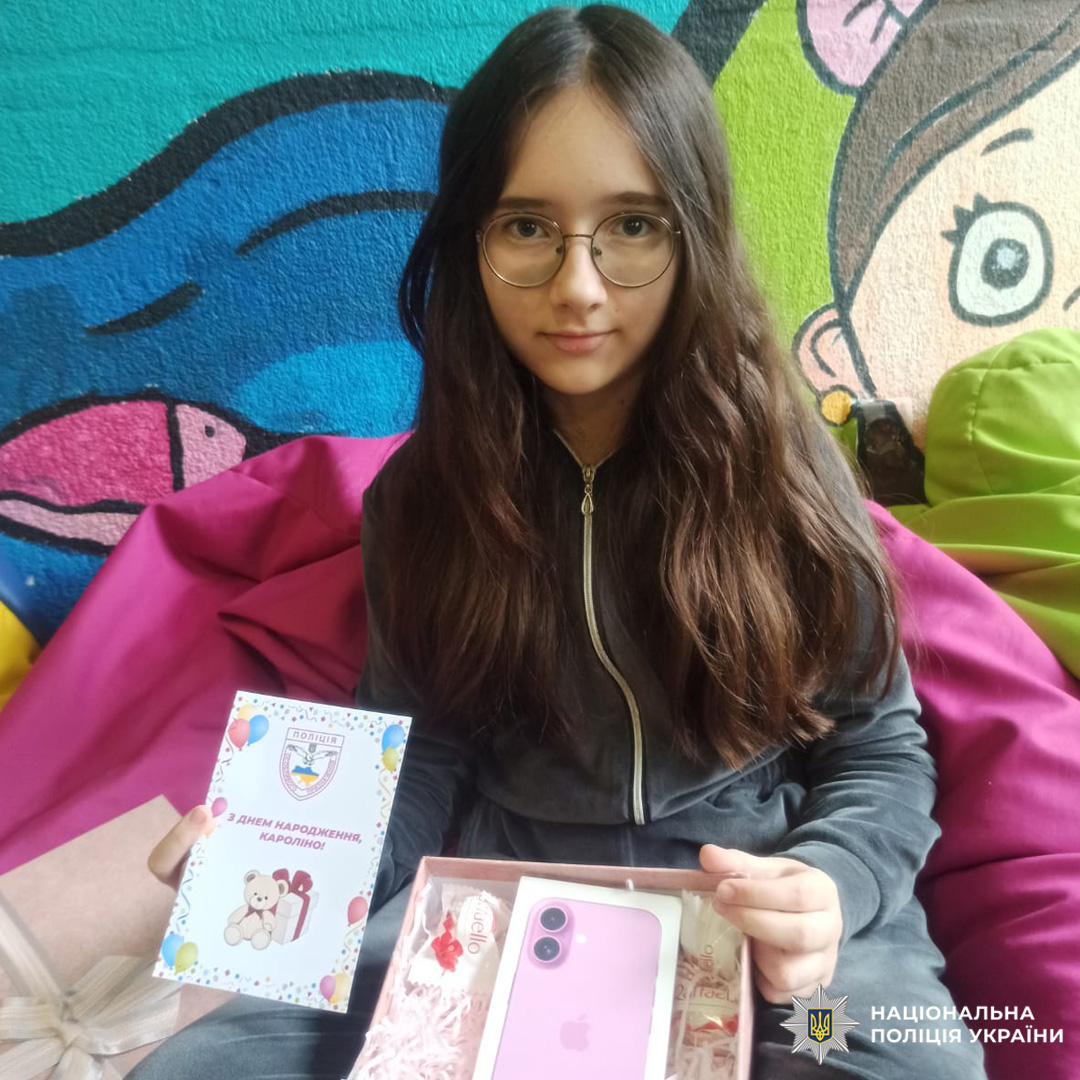 Дівчина отримує подарунок і вітальну листівку з логотипом Національної поліції України під час святкування дня народження.