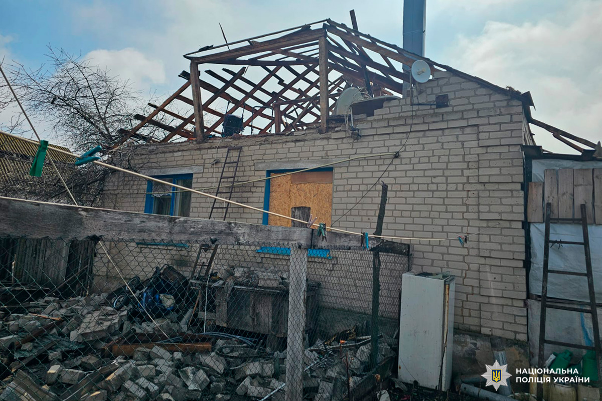 Пошкоджений житловий будинок із частково зруйнованим дахом та розкиданими уламками.